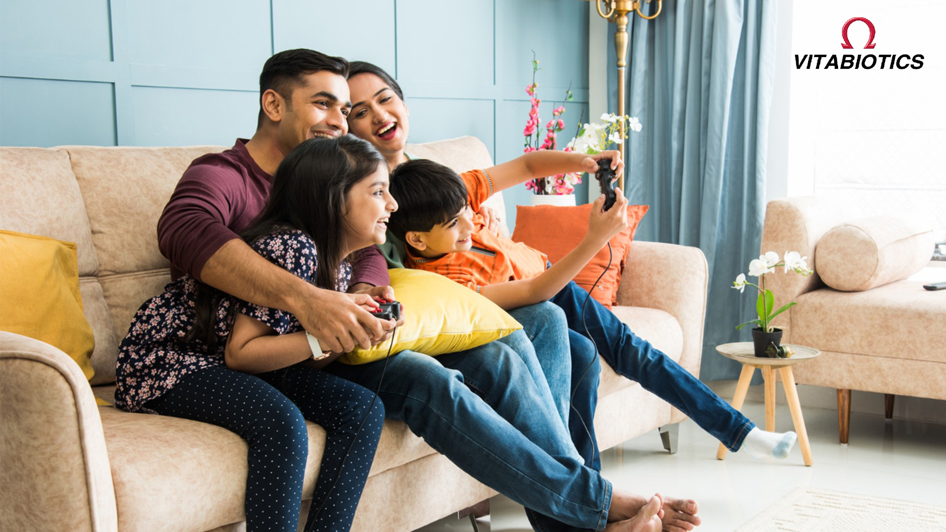 family playing video games together at home, sitting on sofa and enjoying quality time - Vitabiotics lifestyle wellness