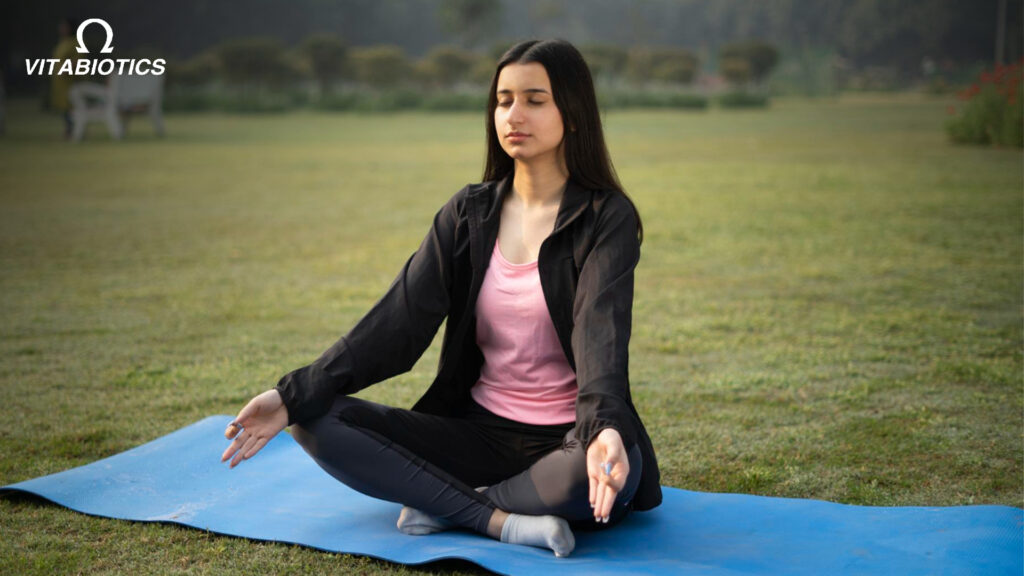Woman meditating outdoors on yoga mat - Vitabiotics wellness.