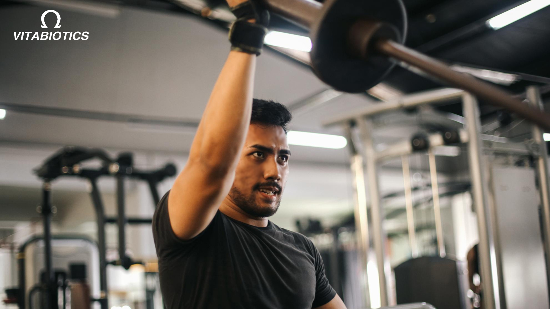 man lifting weights at gym - Vitabiotics health and wellness.